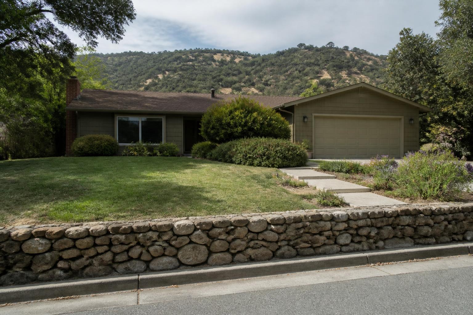 Valley home with a green lawn and stone retaining wall